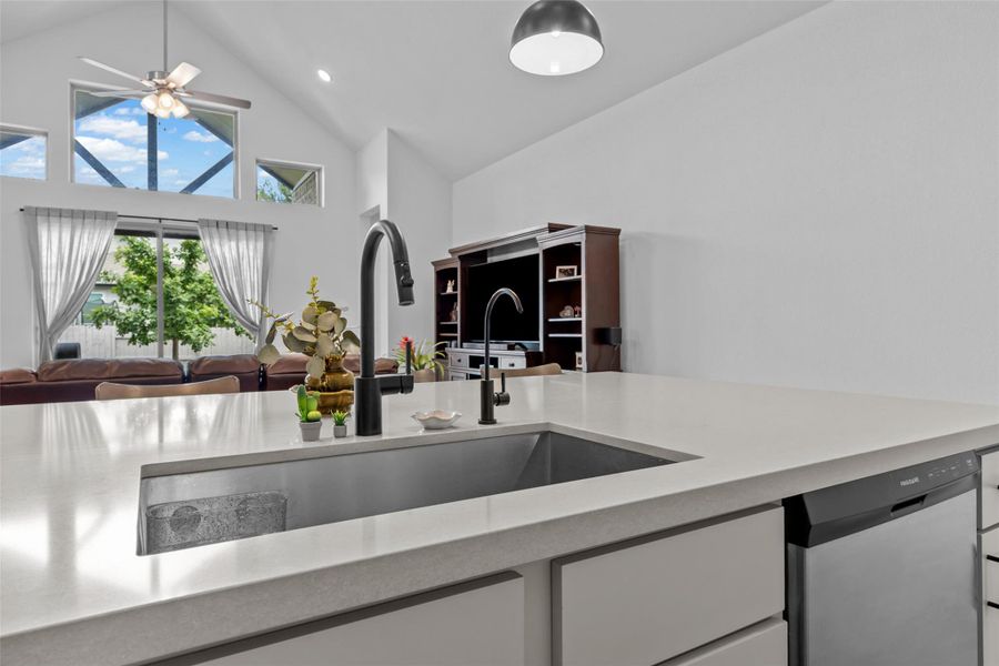 A spacious kitchen with a large island and ample counter space overlooks a cozy living area. A spacious kitchen with a large island and ample counter space overlooks a cozy living area.