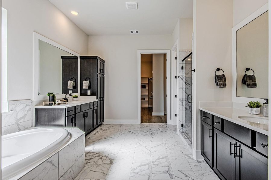 Spacious primary bathroom featuring extensive counter space and dark cabinetry
