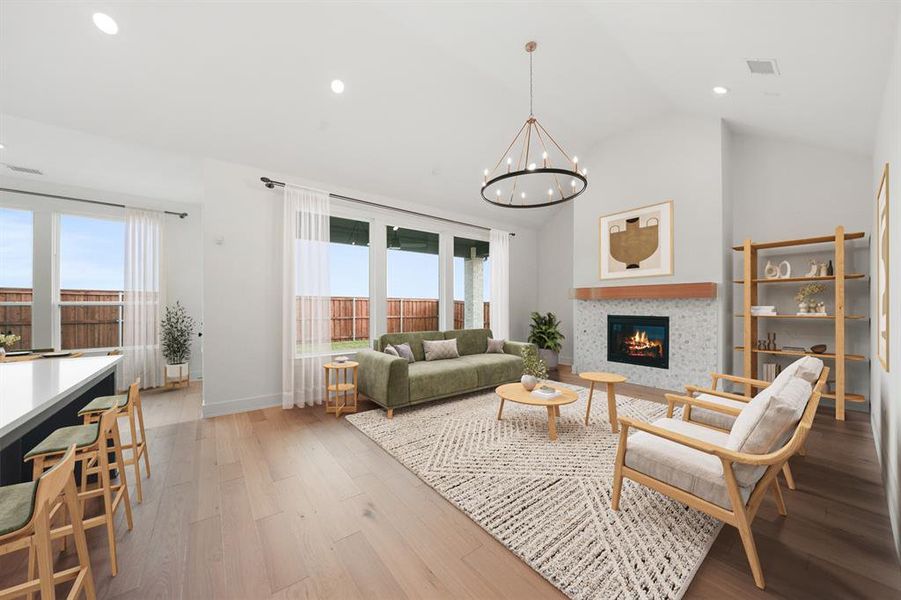 Living room with a tile fireplace, light wood-style floors, healthy amount of natural light, recessed lighting, and lofted ceiling