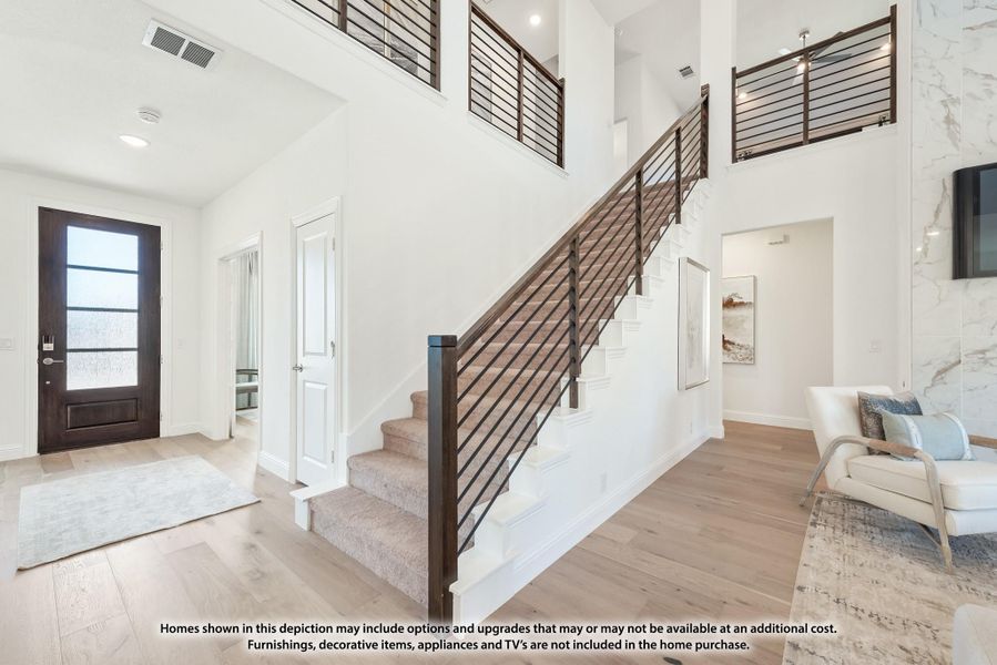 Two-story foyer with wood staircase, dark metal railing, hardwood floors, and a glass-panel front door Two-story foyer with wood staircase, dark metal railing, hardwood floors, and a glass-panel front door