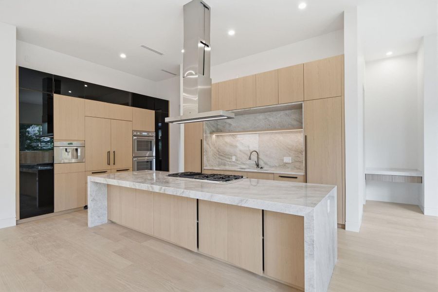 Custom whiteoak cabinetry, and an oversized island. Designer lighting and seamlessflow connect it to the spacious living and dining areas.