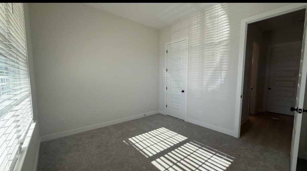 Unfurnished bedroom with dark colored carpet and baseboards