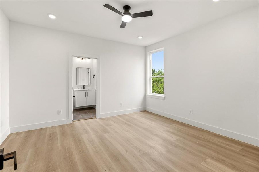 This room features light wood-style flooring, white walls, and a ceiling fan