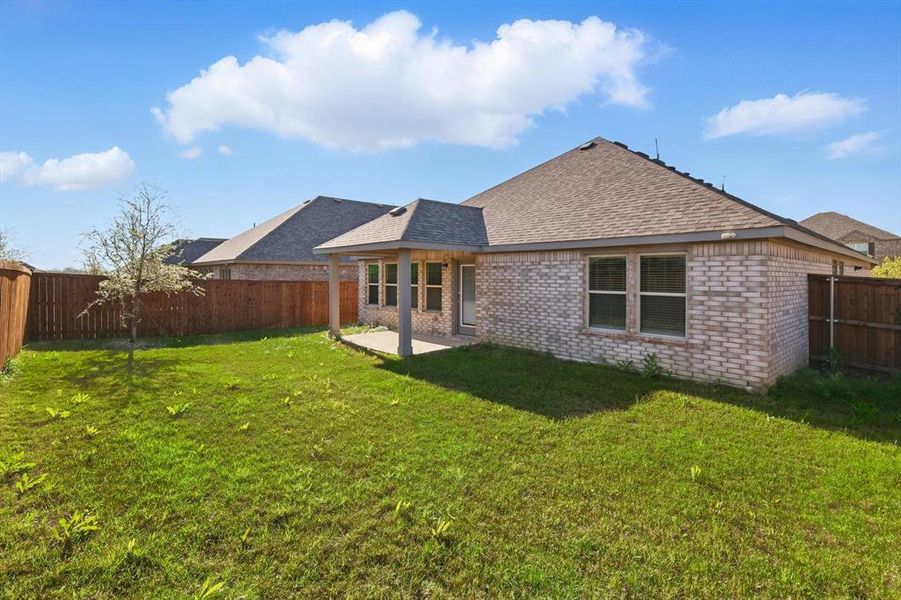 Back of house featuring roof with shingles, brick siding, a fenced backyard, and a patio Back of house featuring roof with shingles, brick siding, a fenced backyard, and a patio