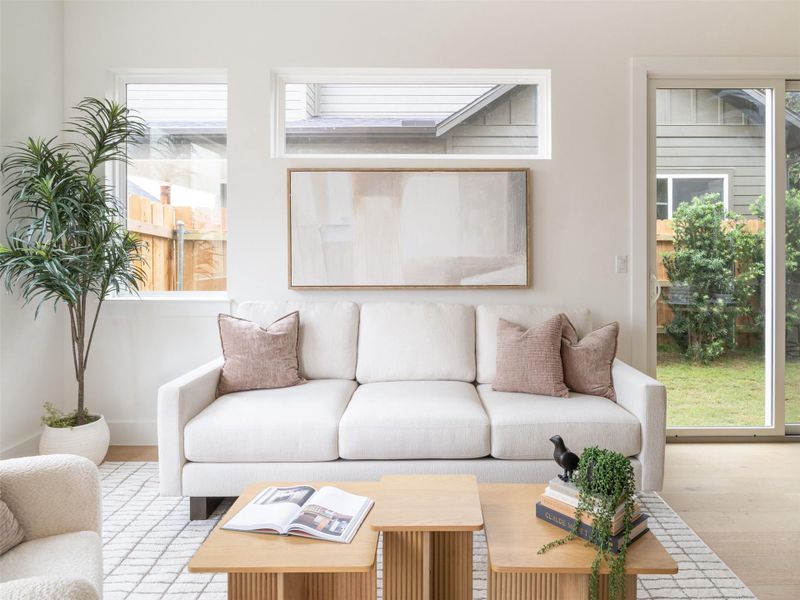 Bright living area featuring wood-finish flooring, a contemporary white sofa, and a patterned area rug