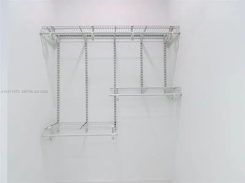 White wire shelving system featuring dual-tier hanging rods and adjustable track-mounted supports