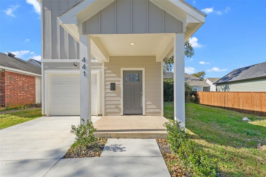 Entrance to property featuring board and batten siding, a garage, a porch, and driveway