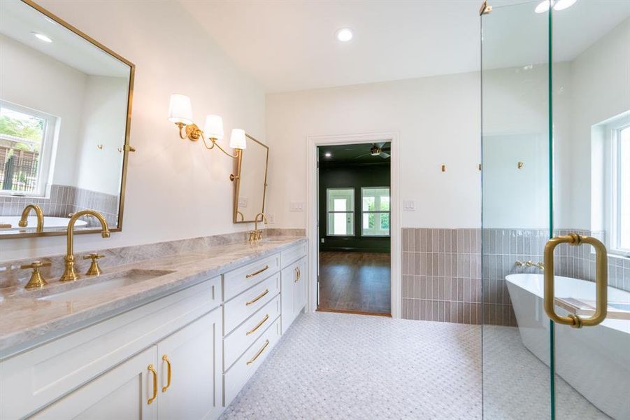 Spacious bathroom featuring a dual vanity with stone countertops, individual framed mirrors, and gold-tone fixtures Spacious bathroom featuring a dual vanity with stone countertops, individual framed mirrors, and gold-tone fixtures