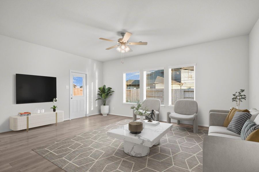 Another virtually staged view of the family area highlights how beautifully the space connects to the dining and kitchen zones. The modern ceiling fan, soft neutral tones, and wide plank flooring create a warm and welcoming atmosphere throughout. Another virtually staged view of the family area highlights how beautifully the space connects to the dining and kitchen zones. The modern ceiling fan, soft neutral tones, and wide plank flooring create a warm and welcoming atmosphere throughout.