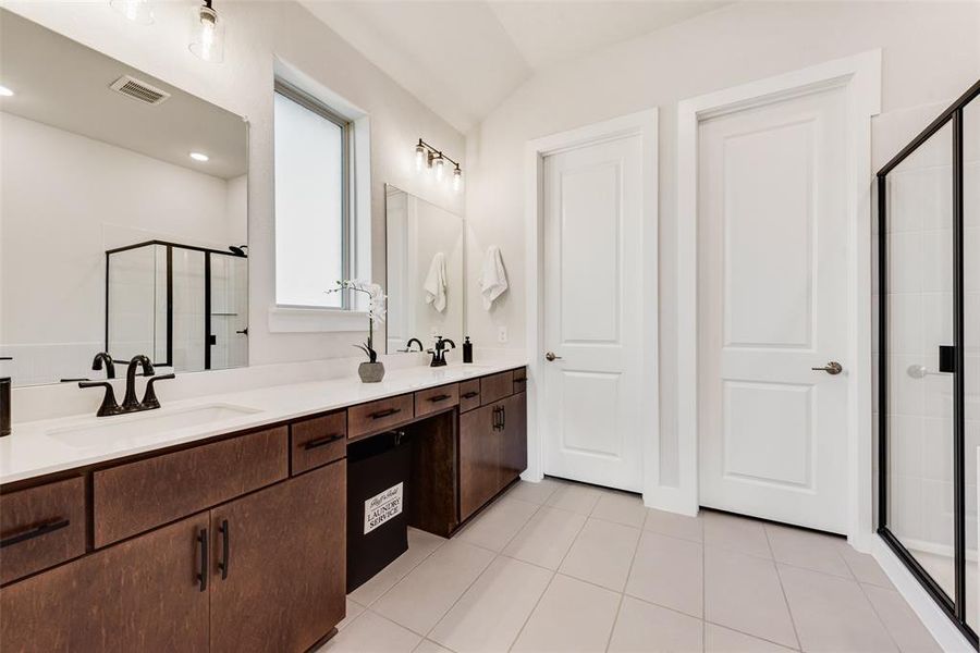Bathroom featuring a stall shower, double vanity, and light tile patterned floors