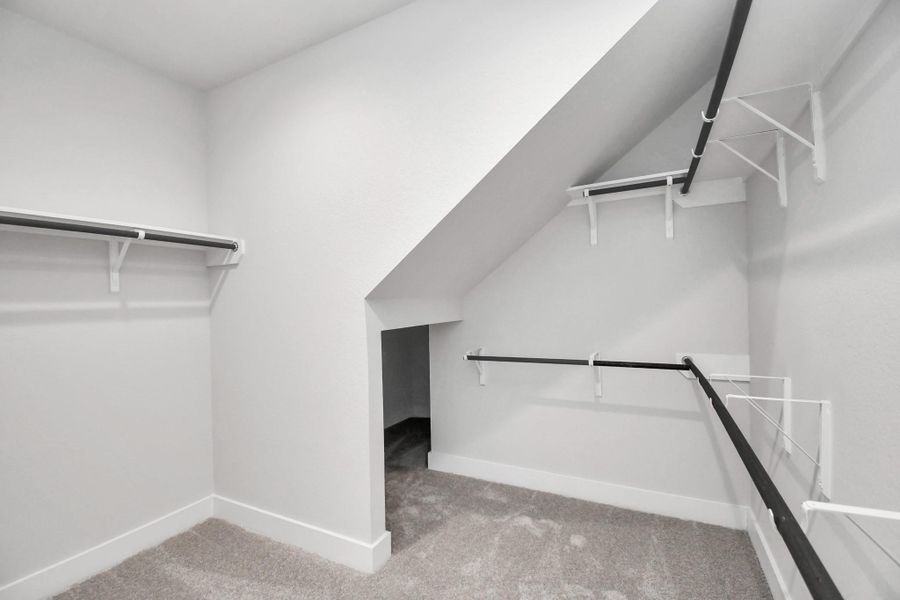 Walk-in closet that epitomizes luxury and practicality. This generously sized space features built-in shelving, offering abundant room for impeccable organization. High ceilings and recessed lighting create a bright and welcoming ambiance. Sample photo of completed home with similar floor plan. Actual colors and selections may vary.