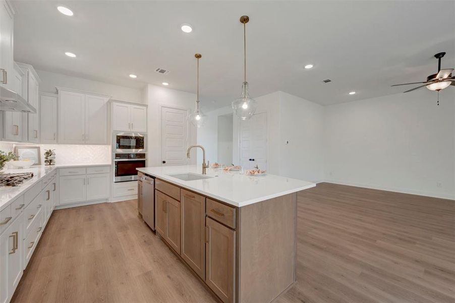 Expansive kitchen featuring white cabinetry, light countertops, and wood-finish flooring Expansive kitchen featuring white cabinetry, light countertops, and wood-finish flooring