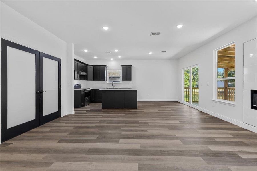 Plank flooring and recessed lighting connect the open living area to the kitchen. Plank flooring and recessed lighting connect the open living area to the kitchen.