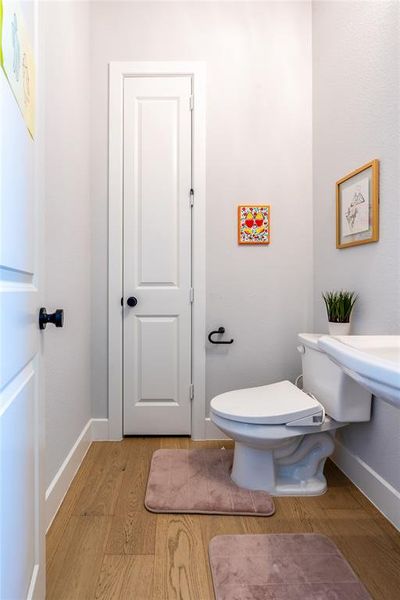 Living room featuring healthy amount of natural light, a towering ceiling, wood finished floors, ceiling fan, and a glass covered fireplace
