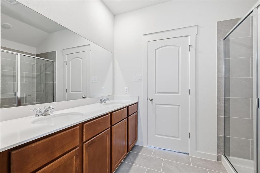 Full bath featuring a stall shower, double vanity, and light tile patterned flooring Full bath featuring a stall shower, double vanity, and light tile patterned flooring
