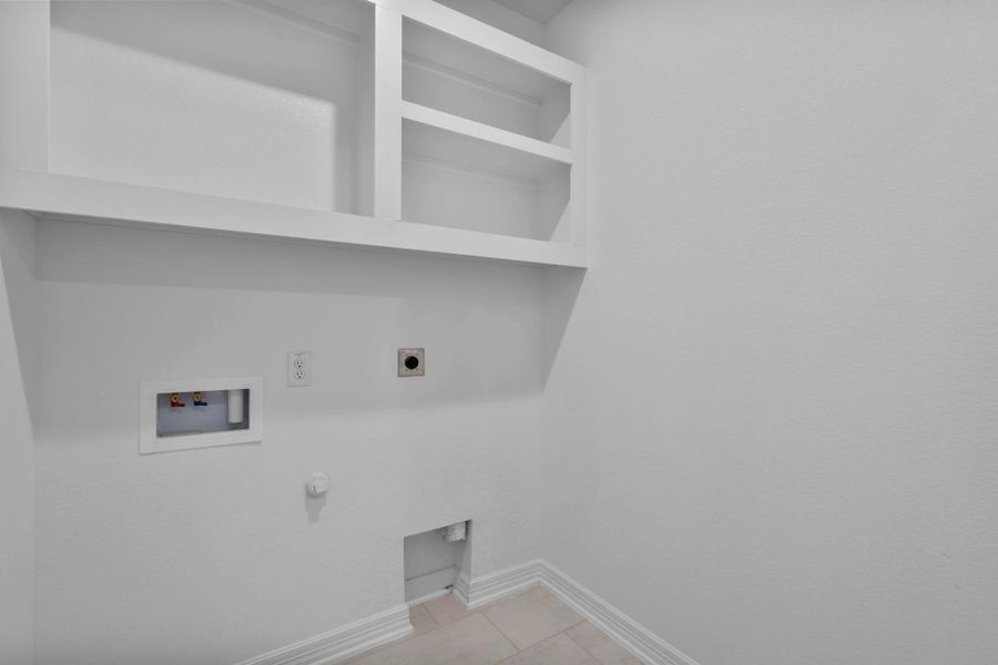 Functional utility room with shelving and convenient laundry hookups.