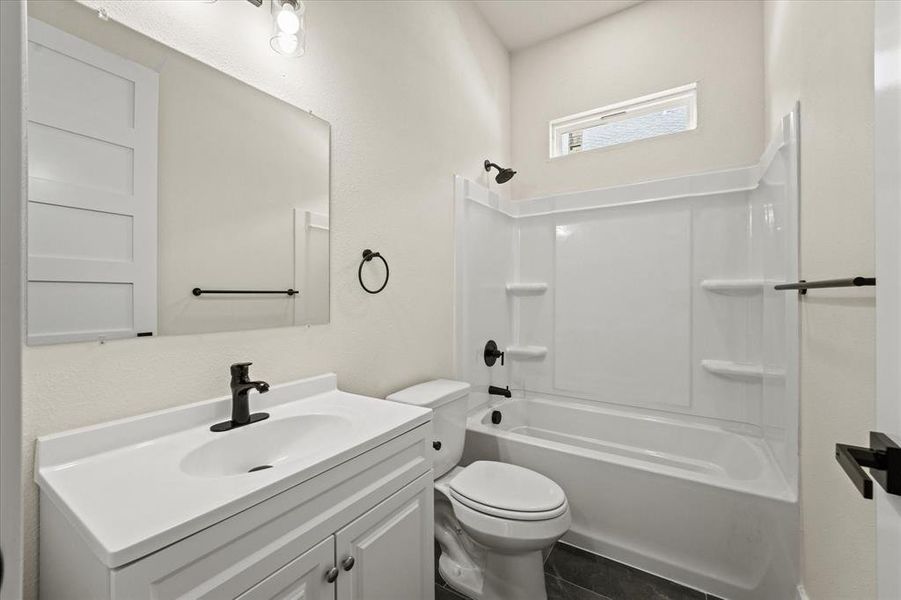 Bathroom featuring bathtub / shower combination, vanity, and a textured wall Bathroom featuring bathtub / shower combination, vanity, and a textured wall