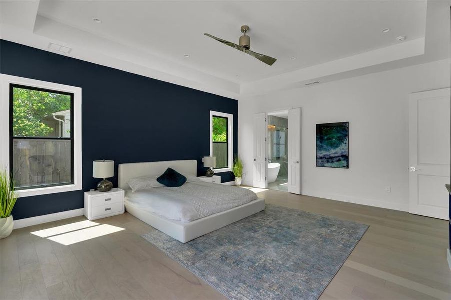 Unfurnished bedroom featuring ceiling fan, a raised ceiling, connected bathroom, and hardwood / wood-style floors