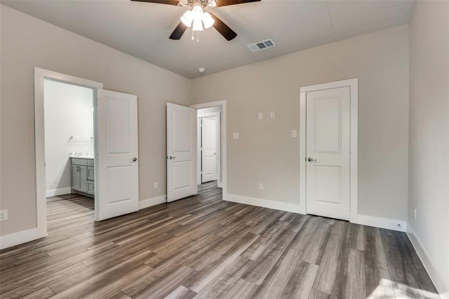 Primary bedroom with connected bathroom, walk-in closet, and ceiling fan