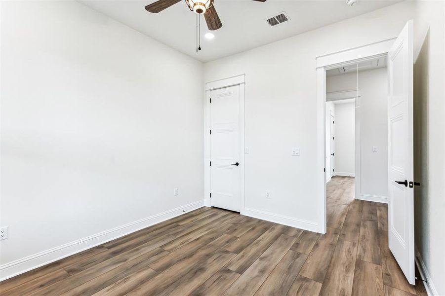 Bedroom 2 with ceiling fan, light hardwood / wood-style flooring, and a walk in closet