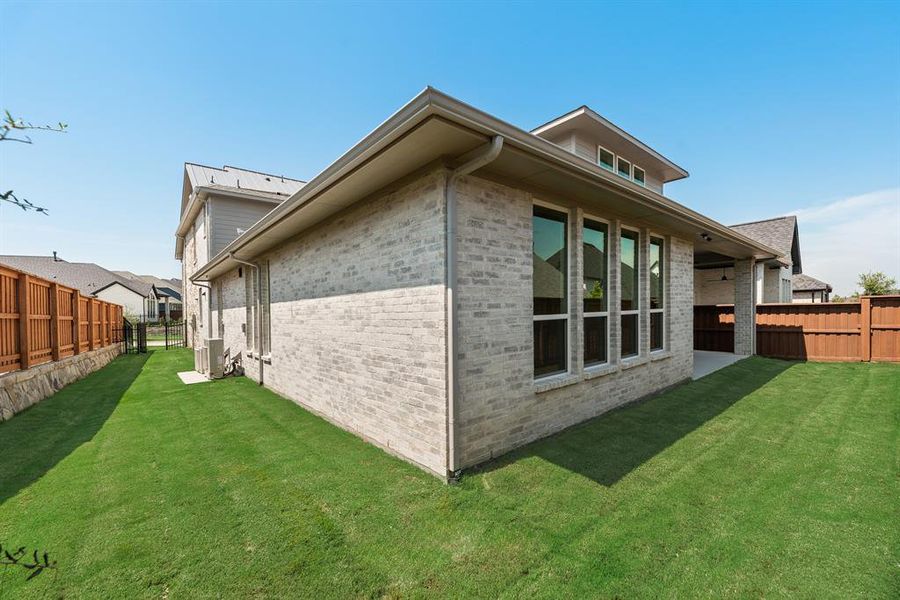 View of property exterior with a fenced backyard, brick siding, and a patio