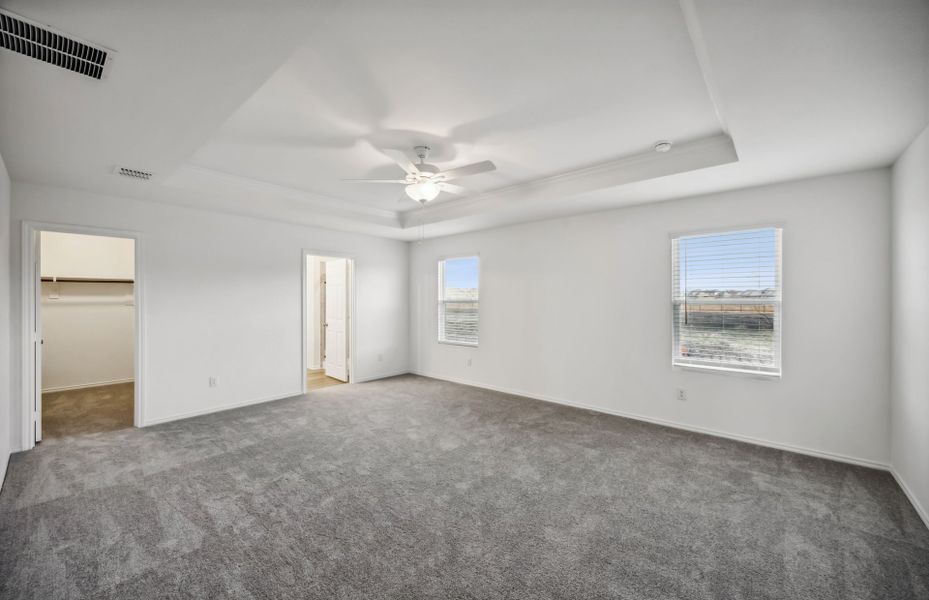 Elegant owner's suite with large windows and tray ceiling *real home pictured