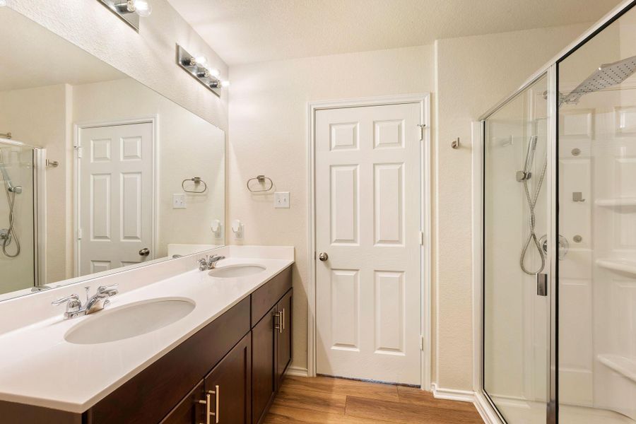 A well-lit bathroom features a double vanity and a contemporary glass-enclosed shower. A well-lit bathroom features a double vanity and a contemporary glass-enclosed shower.