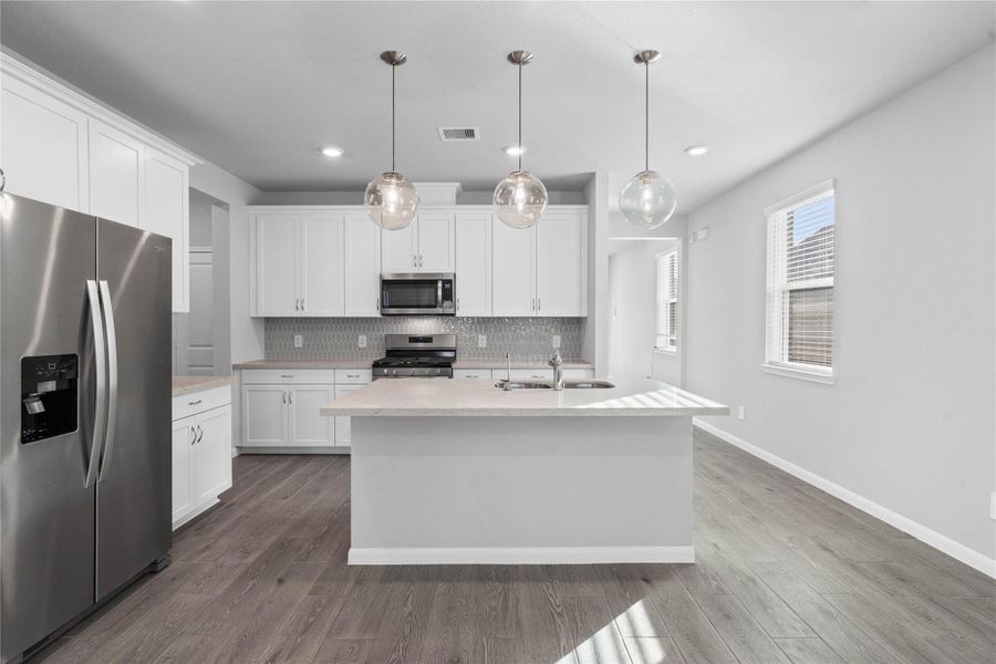 This modern kitchen island features a polished quartz countertop with an undermount double-bowl stainless steel sink, complemented by a Moen Integra chrome faucet and a dedicated reverse osmosis drinking water tap.