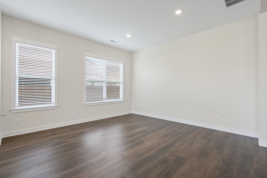 Living space with wood-finish flooring, recessed lighting, two windows with blinds, and white trim Living space with wood-finish flooring, recessed lighting, two windows with blinds, and white trim
