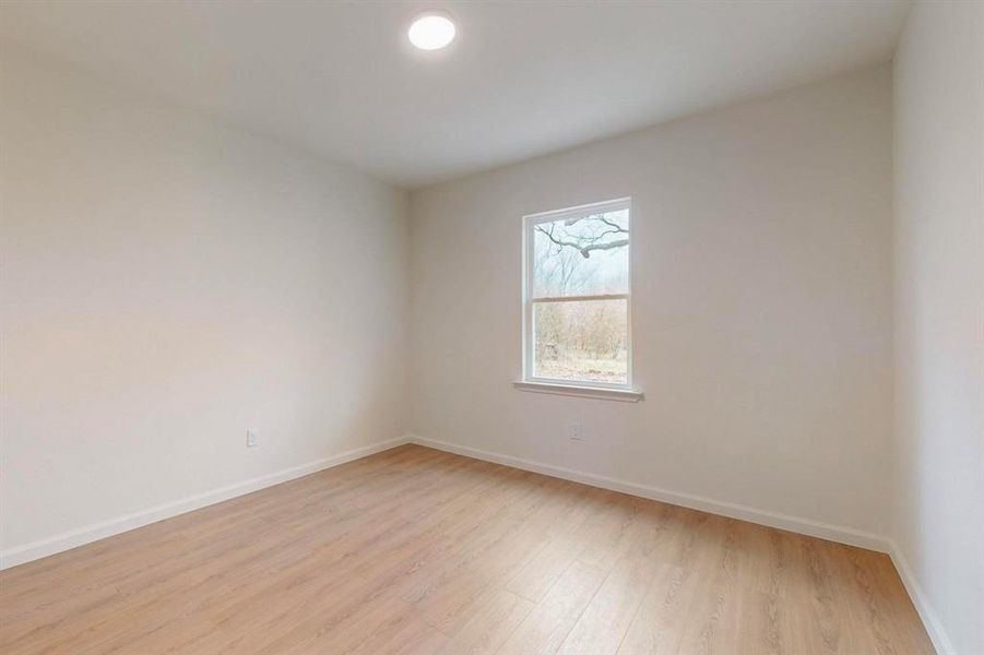Empty room featuring baseboards and light wood finished floors