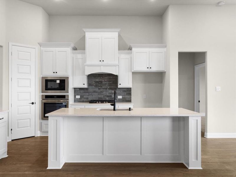 Kitchen featuring white cabinets, light stone countertops, tasteful backsplash, appliances with stainless steel finishes, and a high ceiling