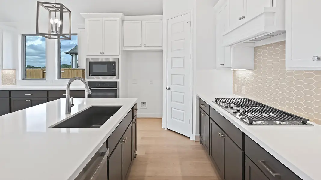 Kitchen with hanging light fixtures, tasteful backsplash, a chandelier, light wood-type flooring, and white cabinets