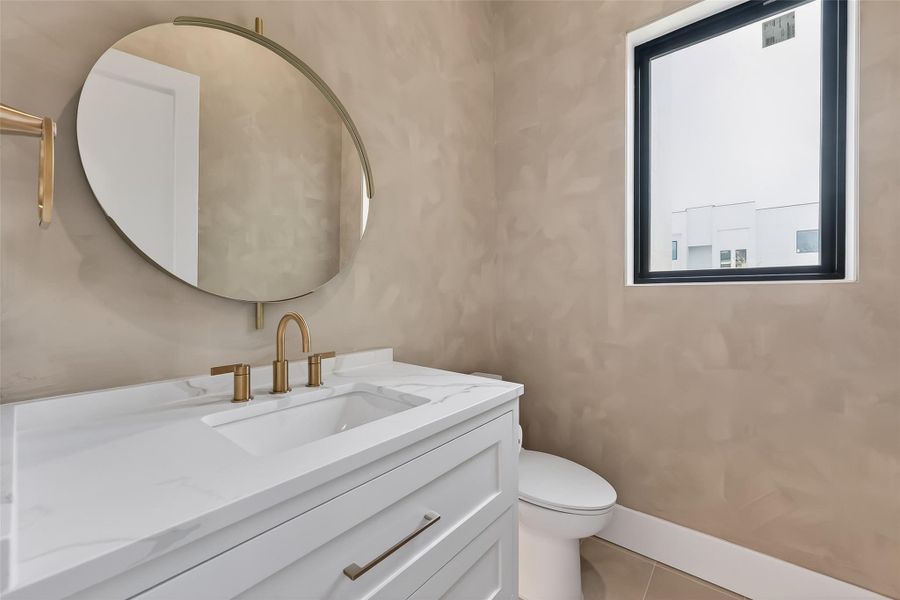 Stylish powder bath on the first floor features a floating vanity, quartz counter, and designer fixtures and wall paint finish.