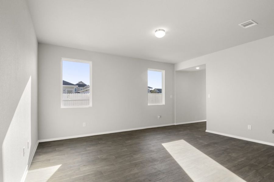 Image of a two story home living room with brown wood-like flooring and light grey painted walls with two windows Image of a two story home living room with brown wood-like flooring and light grey painted walls with two windows