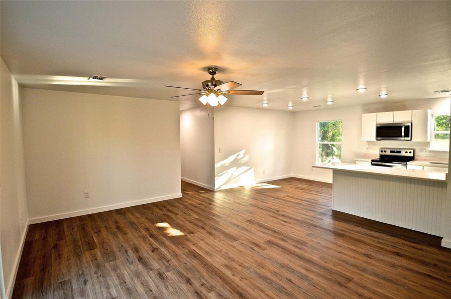 Unfurnished living room featuring dark wood finished floors and ceiling fan