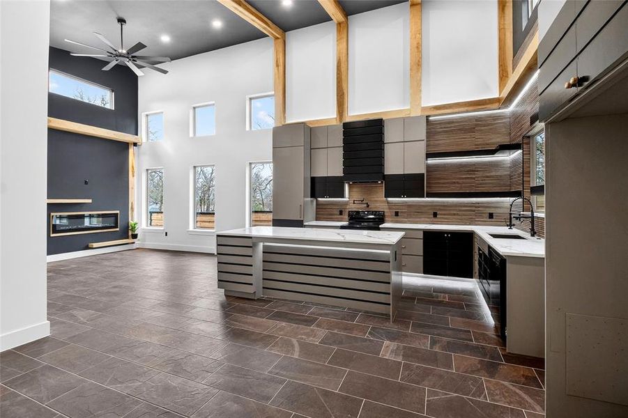 Kitchen with light stone countertops, a high ceiling, a kitchen island, recessed lighting, and a ceiling fan Kitchen with light stone countertops, a high ceiling, a kitchen island, recessed lighting, and a ceiling fan