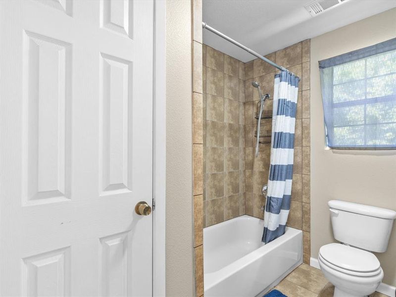 Bathroom featuring shower / tub combo with curtain and tile patterned floors Bathroom featuring shower / tub combo with curtain and tile patterned floors