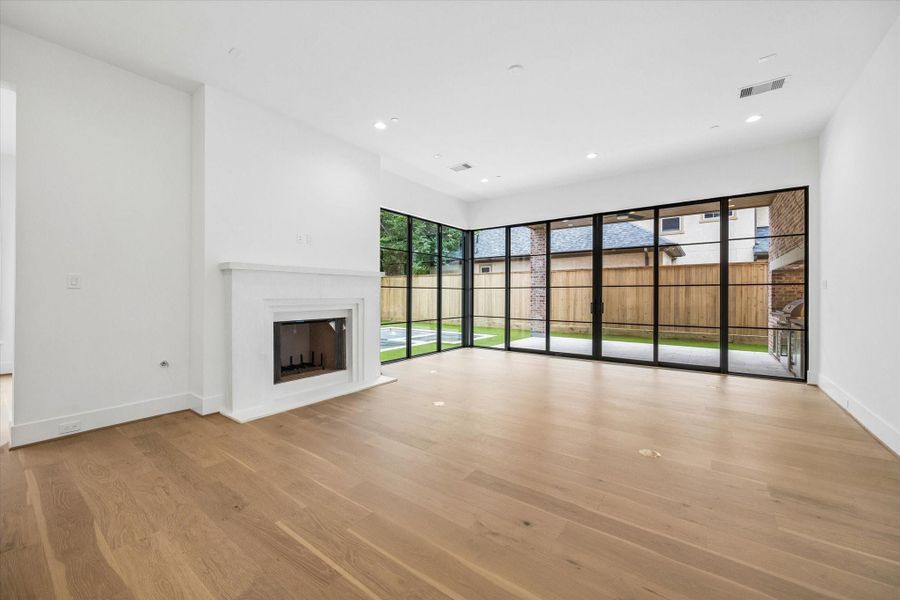 Bright, open-concept living room with sliding doors and expansive corner windows that seamlessly connect to the outdoor living space.
