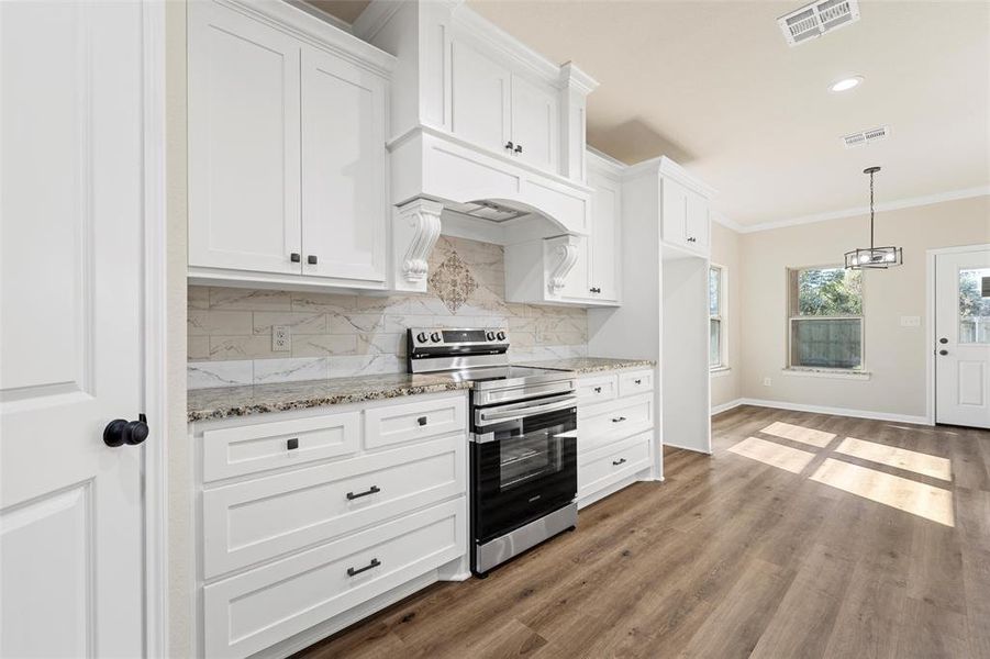Kitchen with stainless steel electric stove, tasteful backsplash, white cabinets, ornamental molding, and wood finished floors