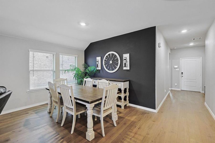 Dining space with vaulted ceiling and light wood-type flooring