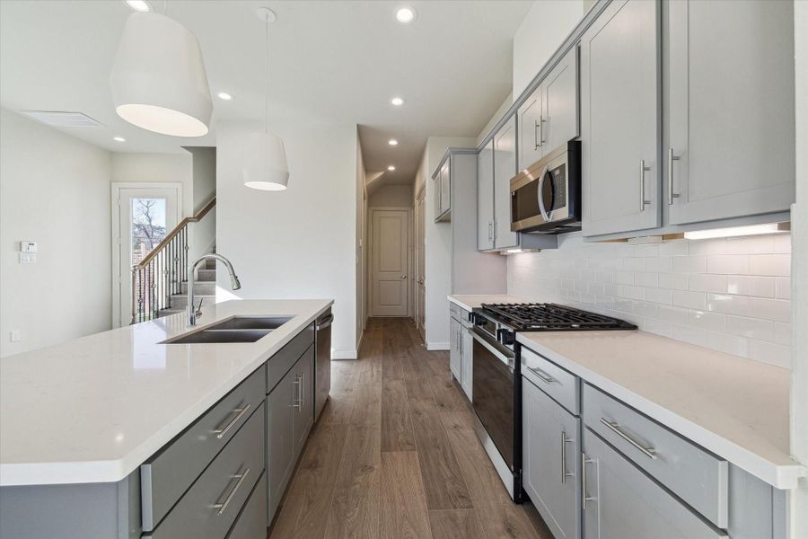 Thoughtfully designed cabinetry, stainless appliances, and quartz countertops create a sleek, functional kitchen built for both everyday living and entertaining.