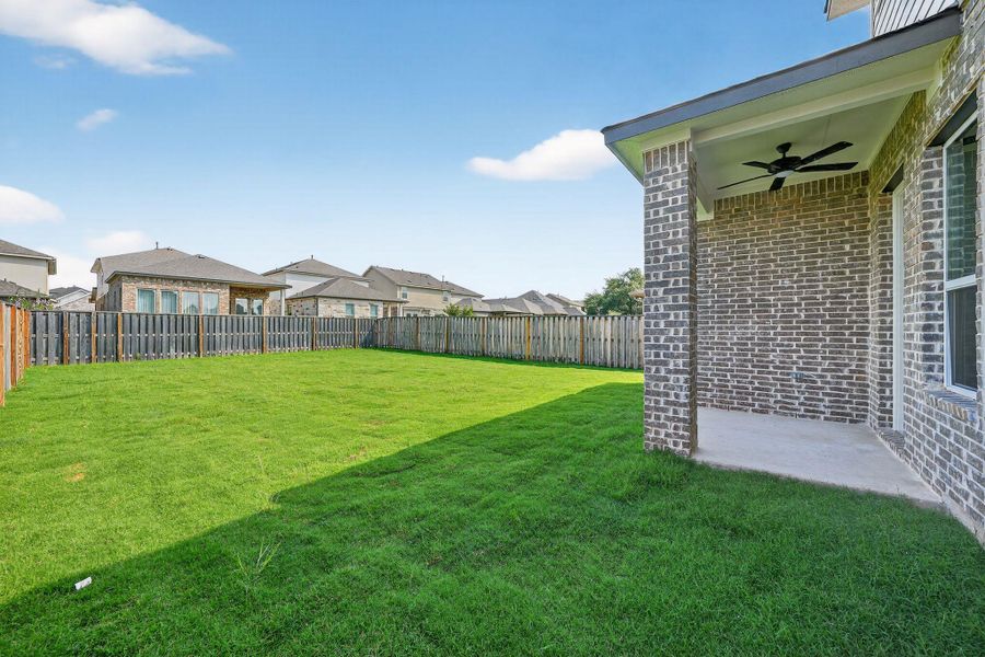 Fenced backyard with a residential view, ceiling fan, and a patio Fenced backyard with a residential view, ceiling fan, and a patio
