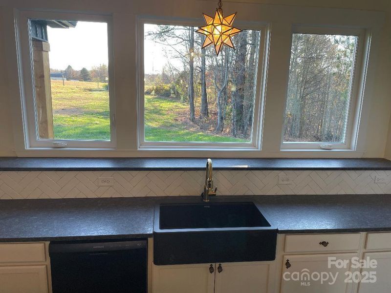 Farmhouse sink where the outdoors is welcomed indoors through the fabulous windows.