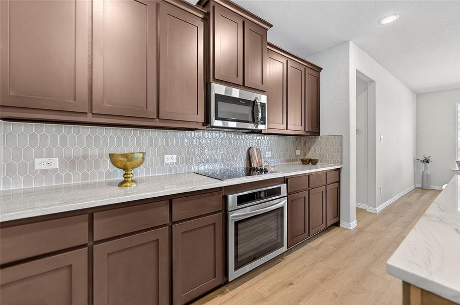 Kitchen with stainless steel appliances, light stone countertops, light wood finished floors, and recessed lighting Kitchen with stainless steel appliances, light stone countertops, light wood finished floors, and recessed lighting