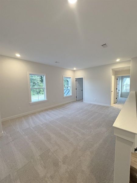 Spacious room with light neutral carpeting, recessed ceiling lighting, and multiple windows Spacious room with light neutral carpeting, recessed ceiling lighting, and multiple windows