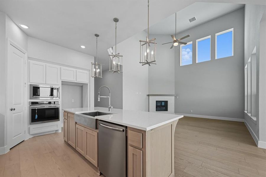 Kitchen featuring light wood-type flooring, pendant lighting, stainless steel appliances, a ceiling fan, and white cabinetry