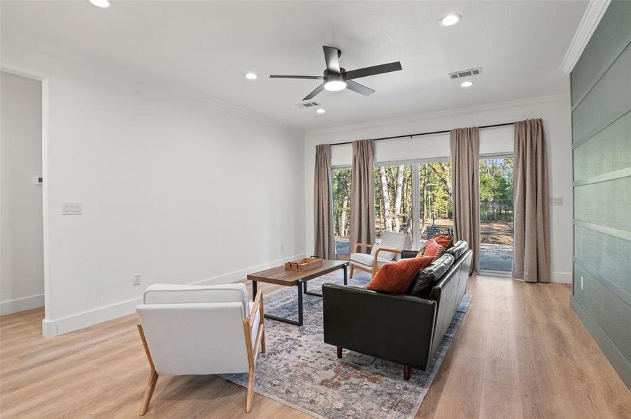 Living room featuring ceiling fan, light hardwood / wood-style floors, and ornamental molding