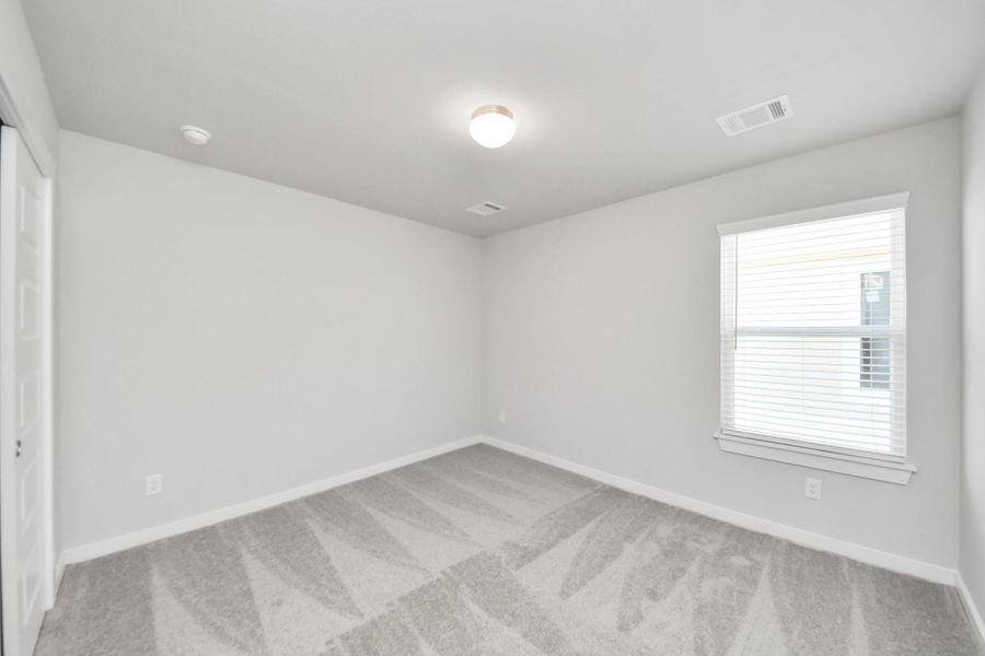 Generously sized secondary bedrooms featuring spacious closets, soft and inviting carpeting underfoot, large windows allowing plenty of natural light. Sample photo of completed home with similar plan. Actual colors and selections may vary. Call for more info.