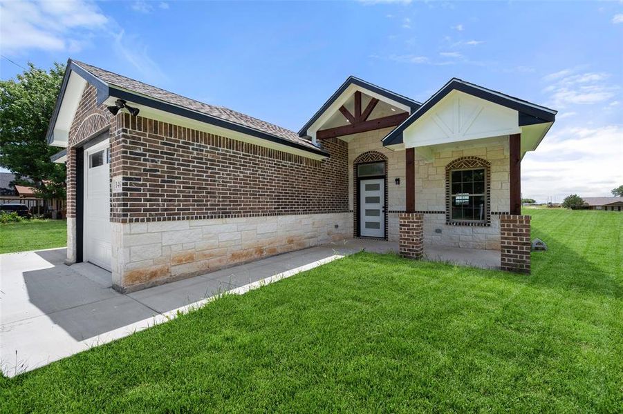 View of front of house with a front yard, brick siding, a shingled roof, and a garage View of front of house with a front yard, brick siding, a shingled roof, and a garage