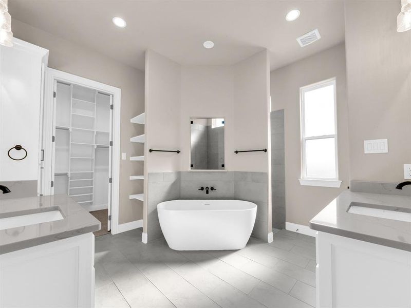 Bathroom featuring tile patterned flooring, built in shelves, vanity, and a bathtub